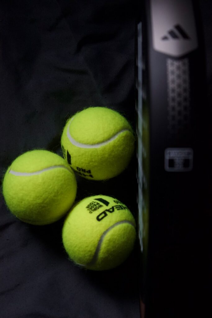 three tennis balls sitting next to a racket